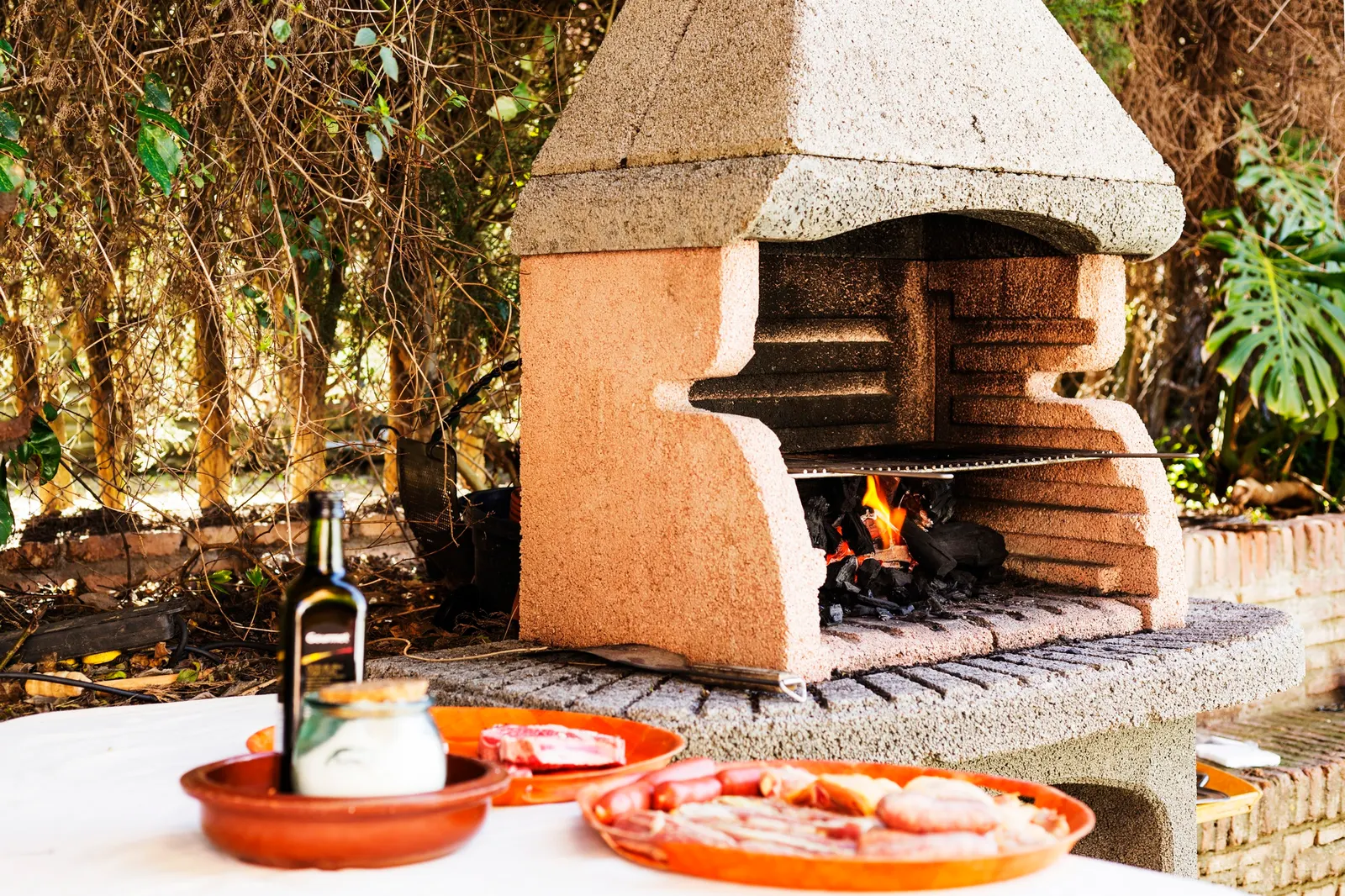 Backyard kitchen island with bar seating and pizza oven in Pilot Point, TX